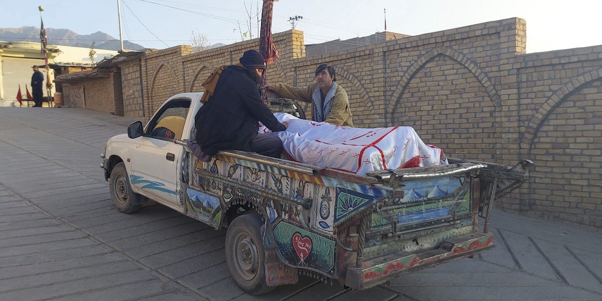 Uomini che in Pakistan trasportano il corpo di una persona uccisa negli scontri (AP Photo/Hussain Ali)