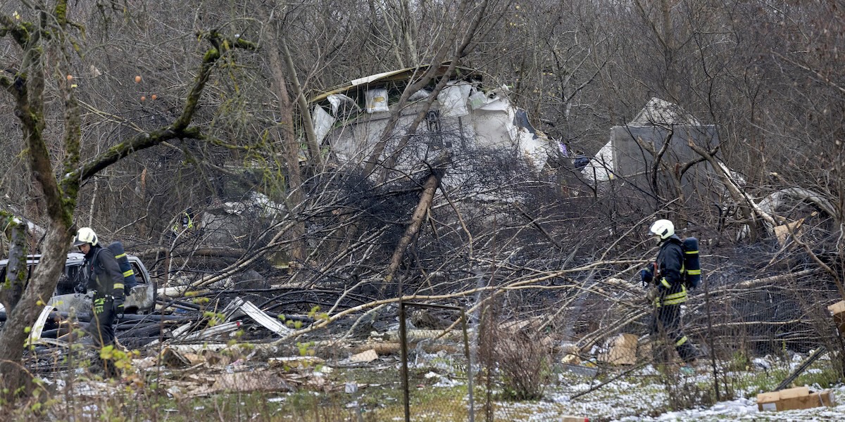 vigili del fuoco vicino a una casa semidistrutta in una zona boscosa