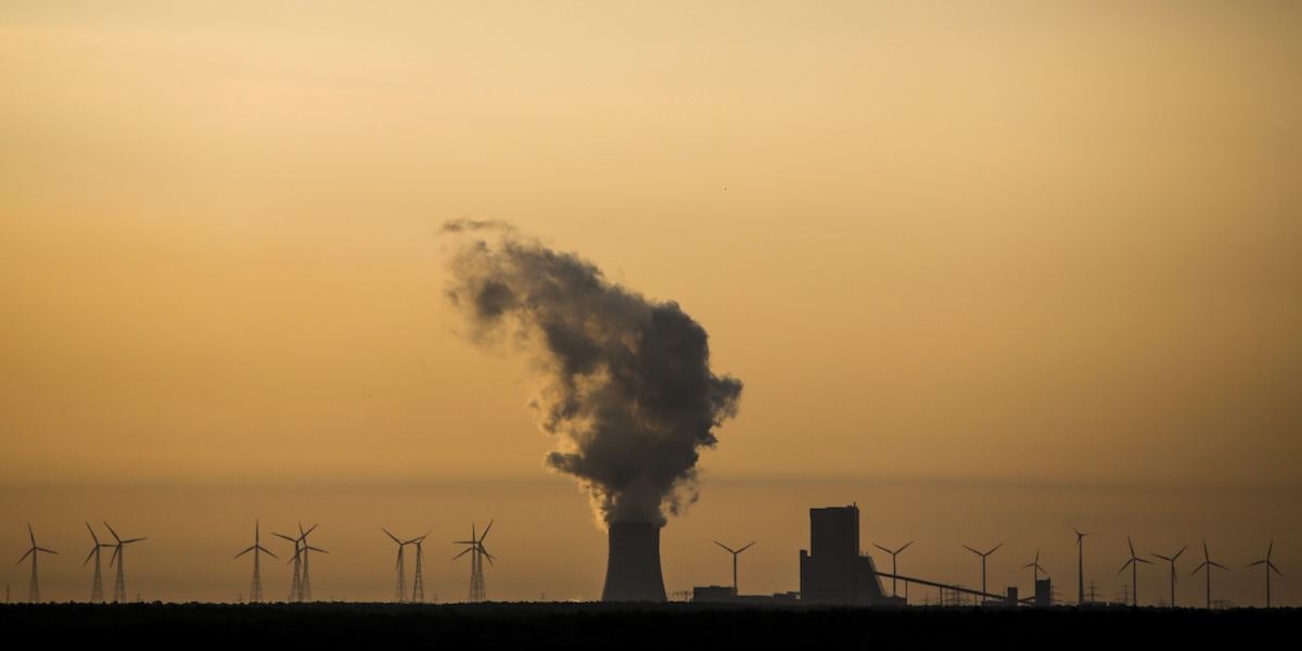 Una nuvola di vapore prodotto da una centrale elettrica a carbone vicino a una serie di pale eoliche