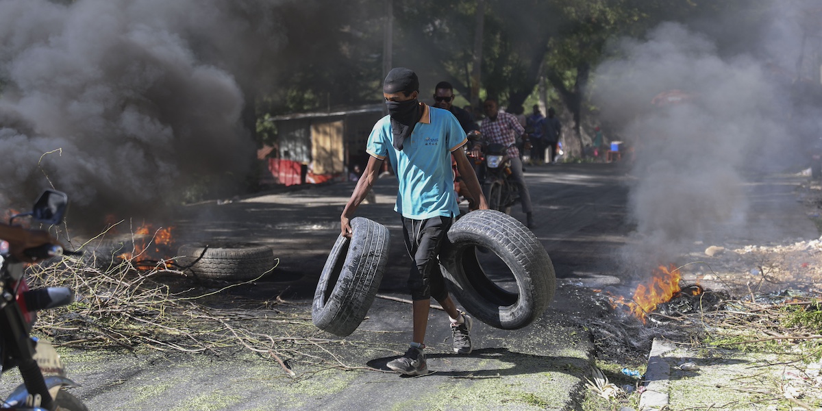 Un residente trasporta degli pneumatici per costruire una barricata contro le bande criminali a Port-au-Prince (AP Photo/Odelyn Joseph)