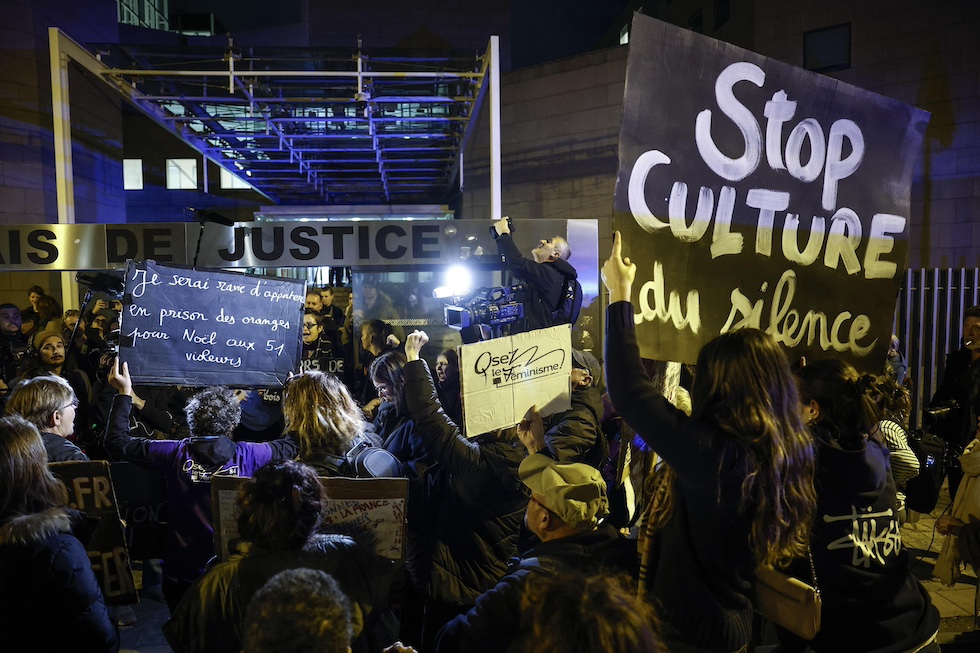 Un gruppo di donne con cartelli con slogan contro la cultura dello stupro manifestano davanti al tribunale di giustizia di Avignone, di sera