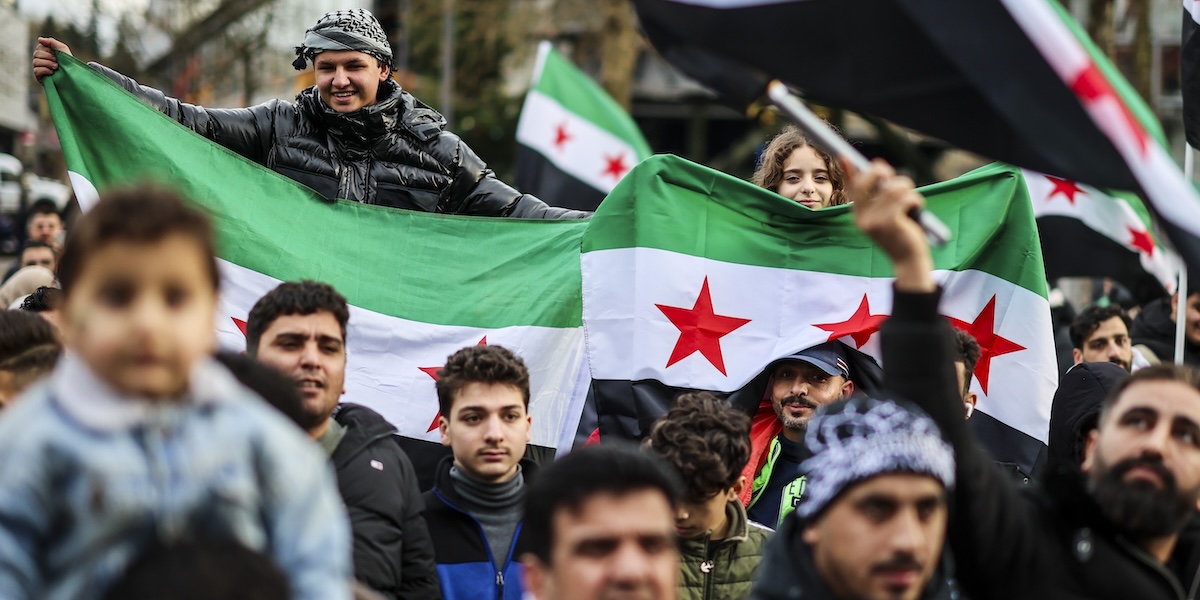 Persone siriane a Wuppertal, in Germania, festeggiano la fine del regime di Assad sventolando la nuova bandiera siriana (Christoph Reichwein/dpa/dpa via AP)