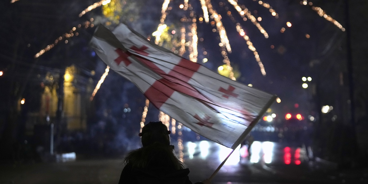 Un manifestante mostra la bandiera georgiana durante una protesta a Tbilisi, in Georgia, il 7 dicembre 2024