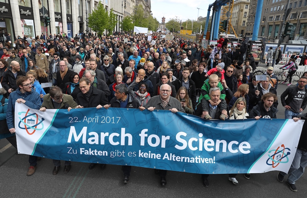 Un gruppo di manifestanti in processione regge uno striscione con la scritta “March for Science”