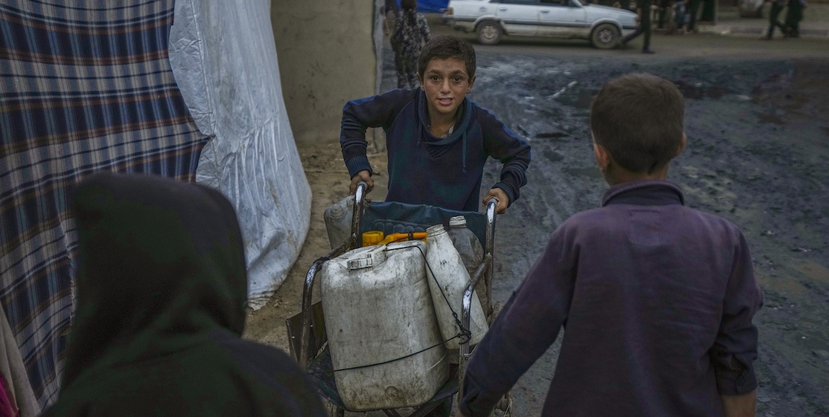 Un bambino a Gaza trasporta delle taniche d'acqua, dicembre 2024