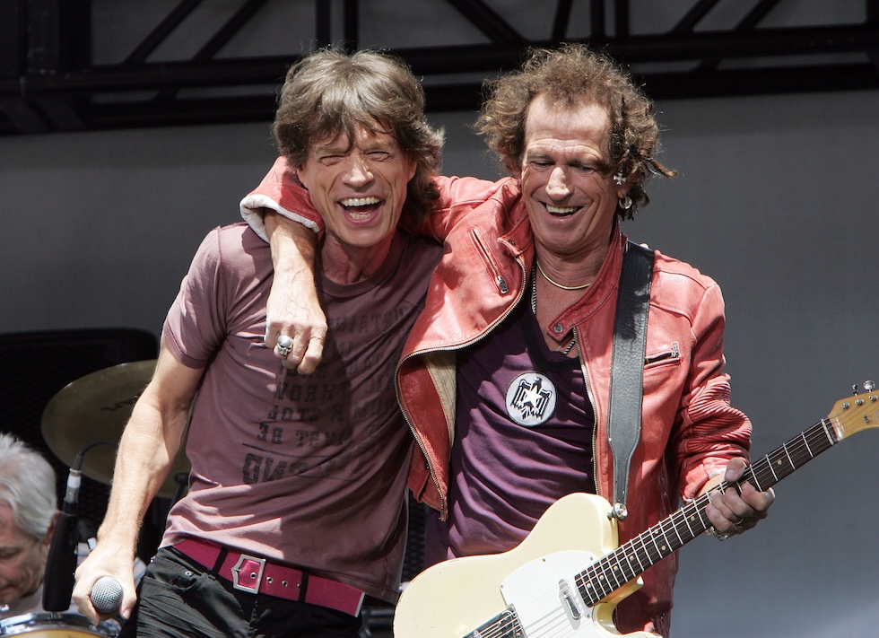 Richards hugs Jagger while holding an electric guitar over his shoulder