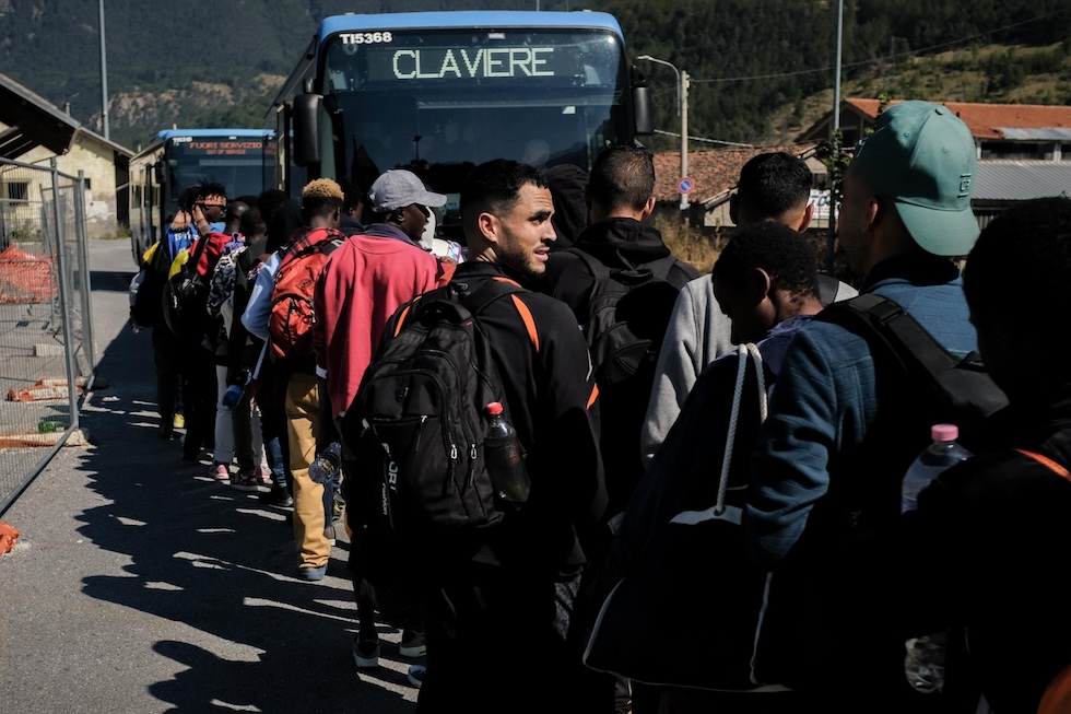 Migranti in attesa di salire sul bus che li porterà a Claviere 