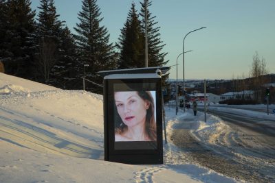 Isabelle Huppert su uno schermo pubblicitario di una fermata dell'autobus di Reykjavík